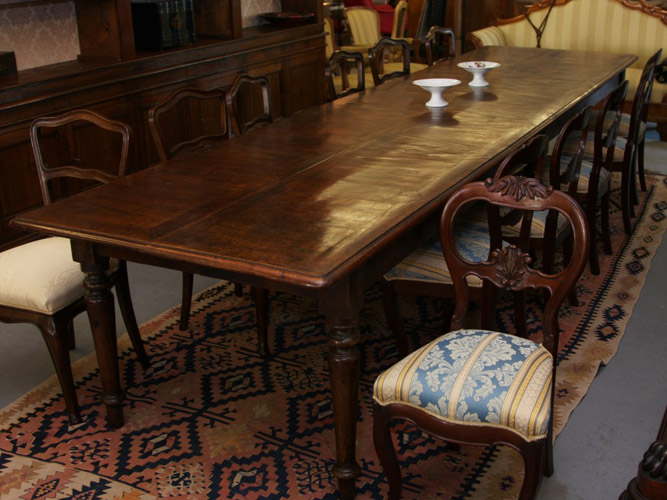 Art.TP.1 - Importante tavolo da pranzo/riunione, interamente in legno di noce con piano lastronato noce a riquadri geometrici, sei gambe tornite.